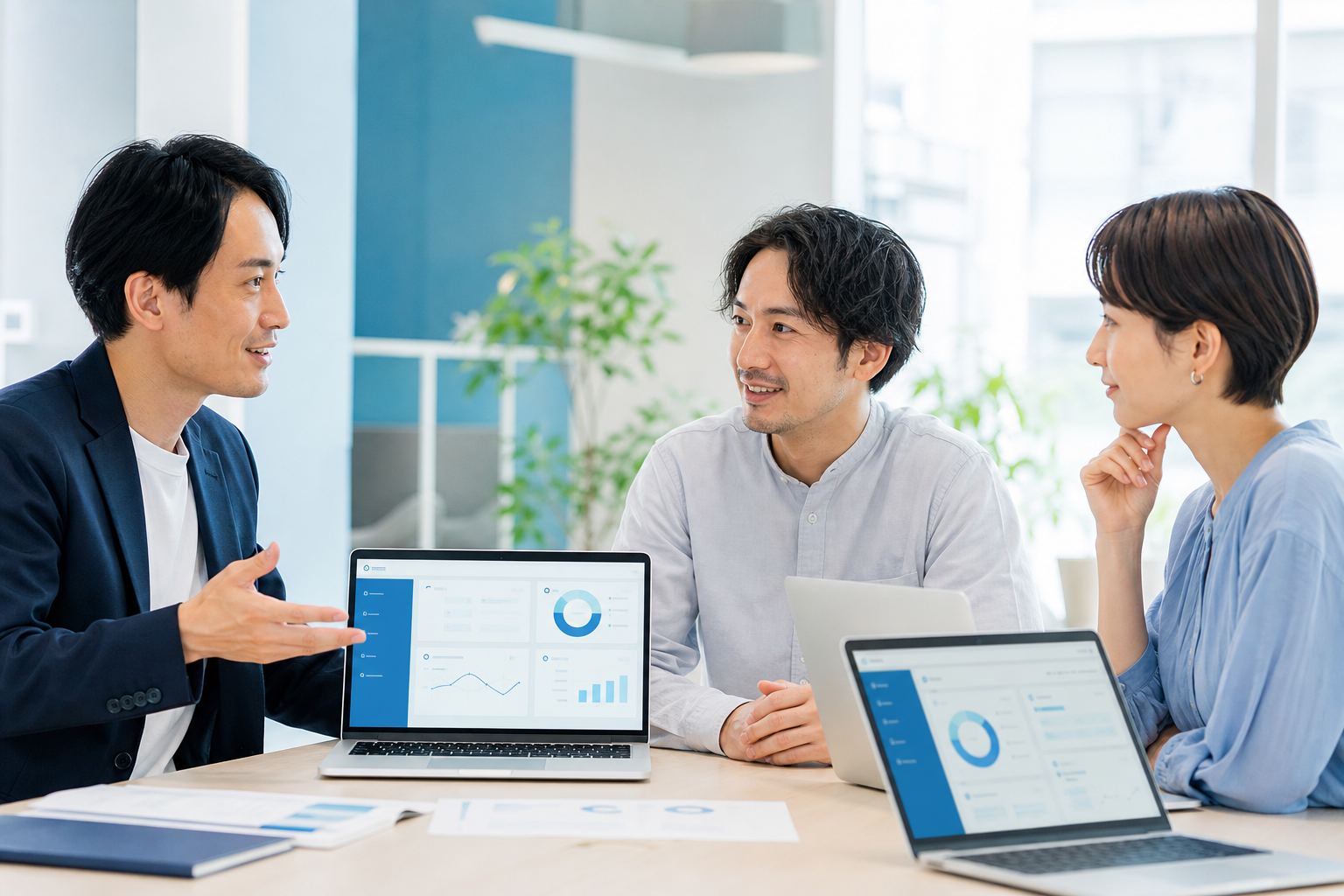 日本のWebディレクターが、経験豊富なWordPressエンジニアとWebデザイナーの二人に相談している、信頼感のあるオフィスミーティング風景。ノートパソコンには抽象化されたWebサイト管理画面や保守状況のビジュアルが表示されているが、文字・ロゴ・ブランド名は一切見えない。三人が落ち着いて課題を共有し、専門家が丁寧に説明している様子から、安心して保守を任せられる技術力、適切な運用、長期的なパートナーシップを表現する。明るく清潔な現代的オフィス、自然光、青と白を基調にした落ち着いた配色、誠実で温かい雰囲気、リアルな人物描写、洗練された企業向けWebサービスのエディトリアル写真、自然な表情と構図、横長、余白を活かした高品質なビジュアル。